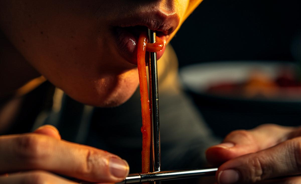 Menschen essen Spaghetti durch einen Strohhalm und erfahrene Feinschmecker hören nie auf zu schwärmen